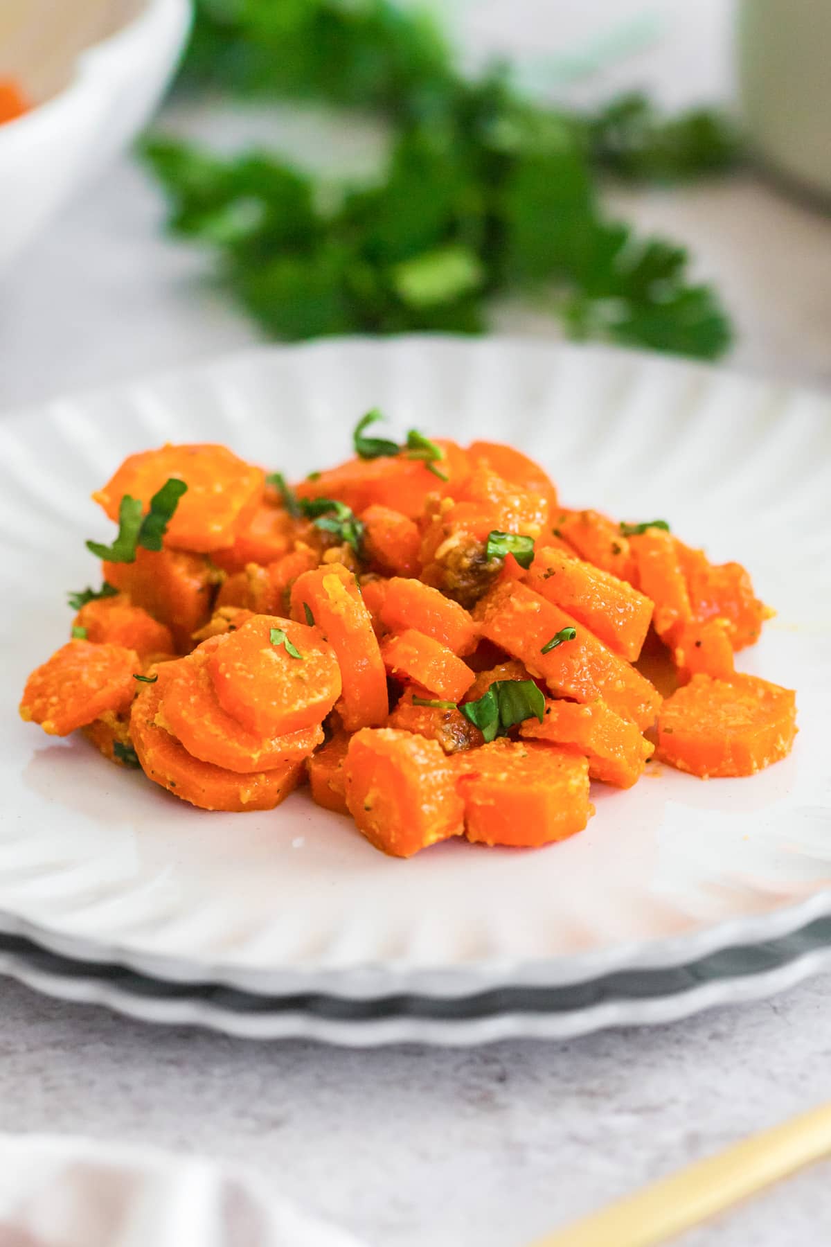 A serving of sliced cooked glazed honey mustard carrots carrots garnished with chopped herbs on a plate.
