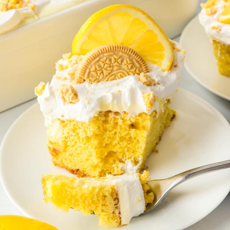 A slice of lemon poke cake on a plate with a bite missing and on a fork.