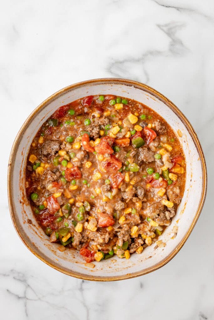 A bowl filled with a cooked ground beef, vegetable and tomato mixture for church supper spaghetti.