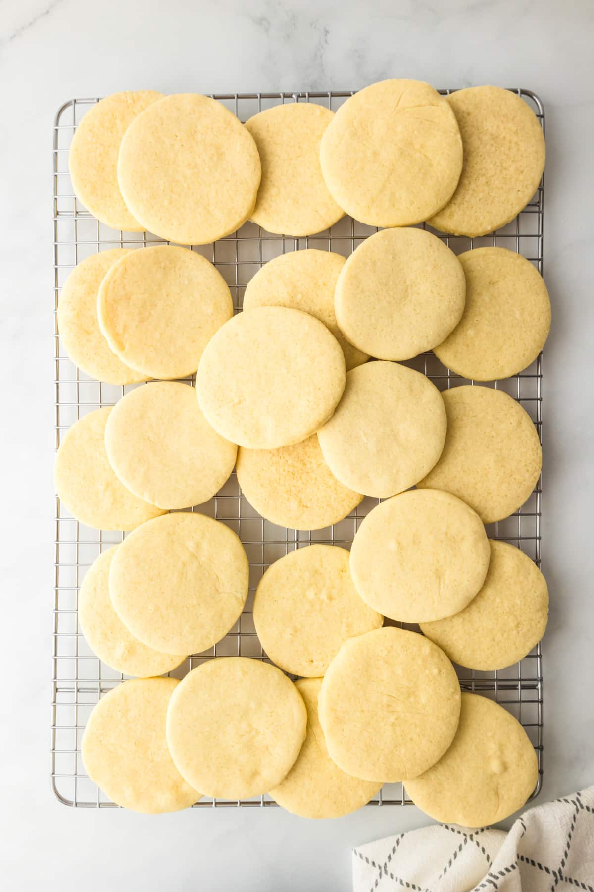 Round sugar cookies layered on a wire cooling rack from above for fruit pizza cookies.