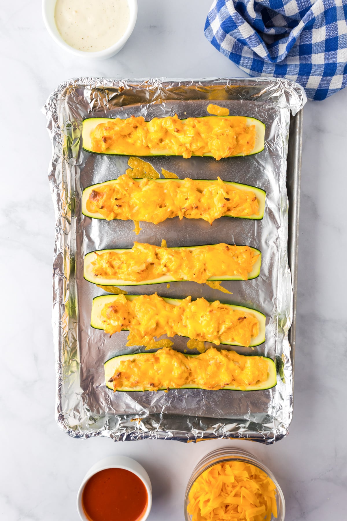Six zucchini halves filled with a cheesy buffalo chicken mixture topped with cheese.