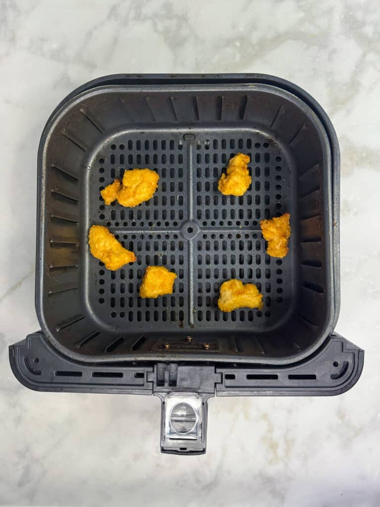 Cooked chicken nuggets in an air fryer base for a chicken nugget wrap.
