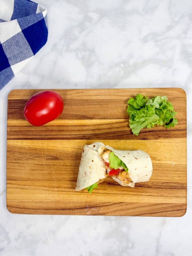 A chicken nugget wrap sliced on a cutting board.