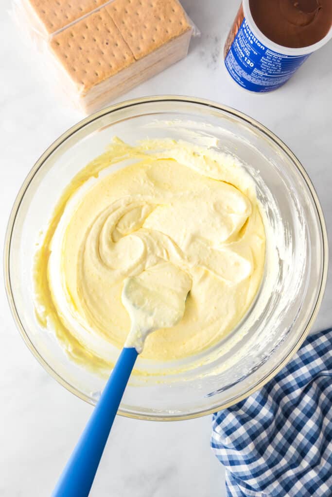 A glass bowl filled with creamy vanilla pudding after folding in the whipped topping for chocolate eclair icebox cake.