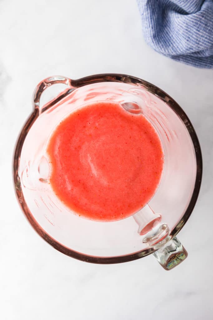 A glass blender from overhead filled with blended frozen strawberry lemonade.