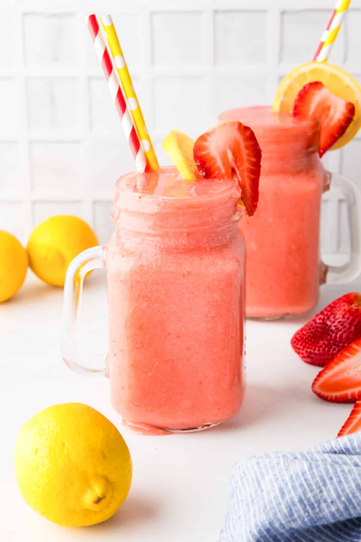 Two mason jar glasses filled with frozen strawberry lemonade.