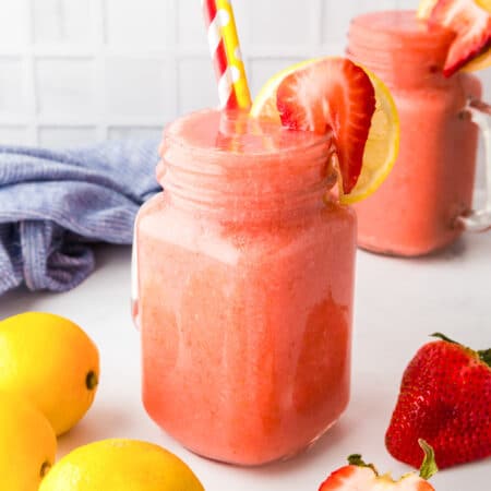 Frozen strawberry lemonade in a mason jar topped with a fresh berry.