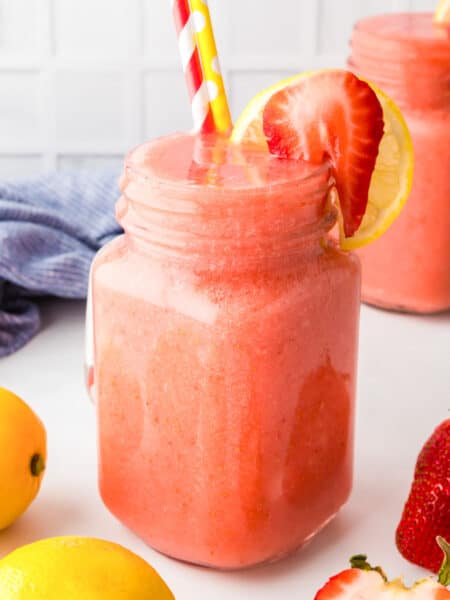 Frozen strawberry lemonade in a mason jar topped with a fresh berry.