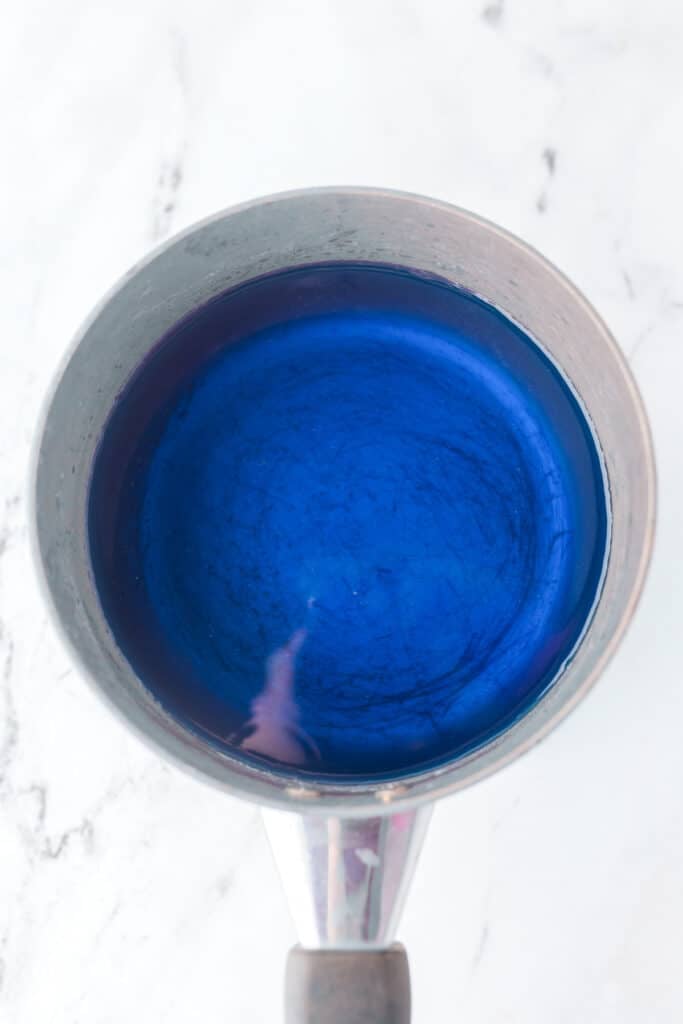 A metal saucepan filled with a bright blue liquid jello.