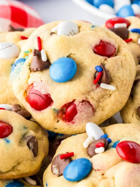 A close-up of cookies with red, white, and blue M&M cookies piled high on a plate.