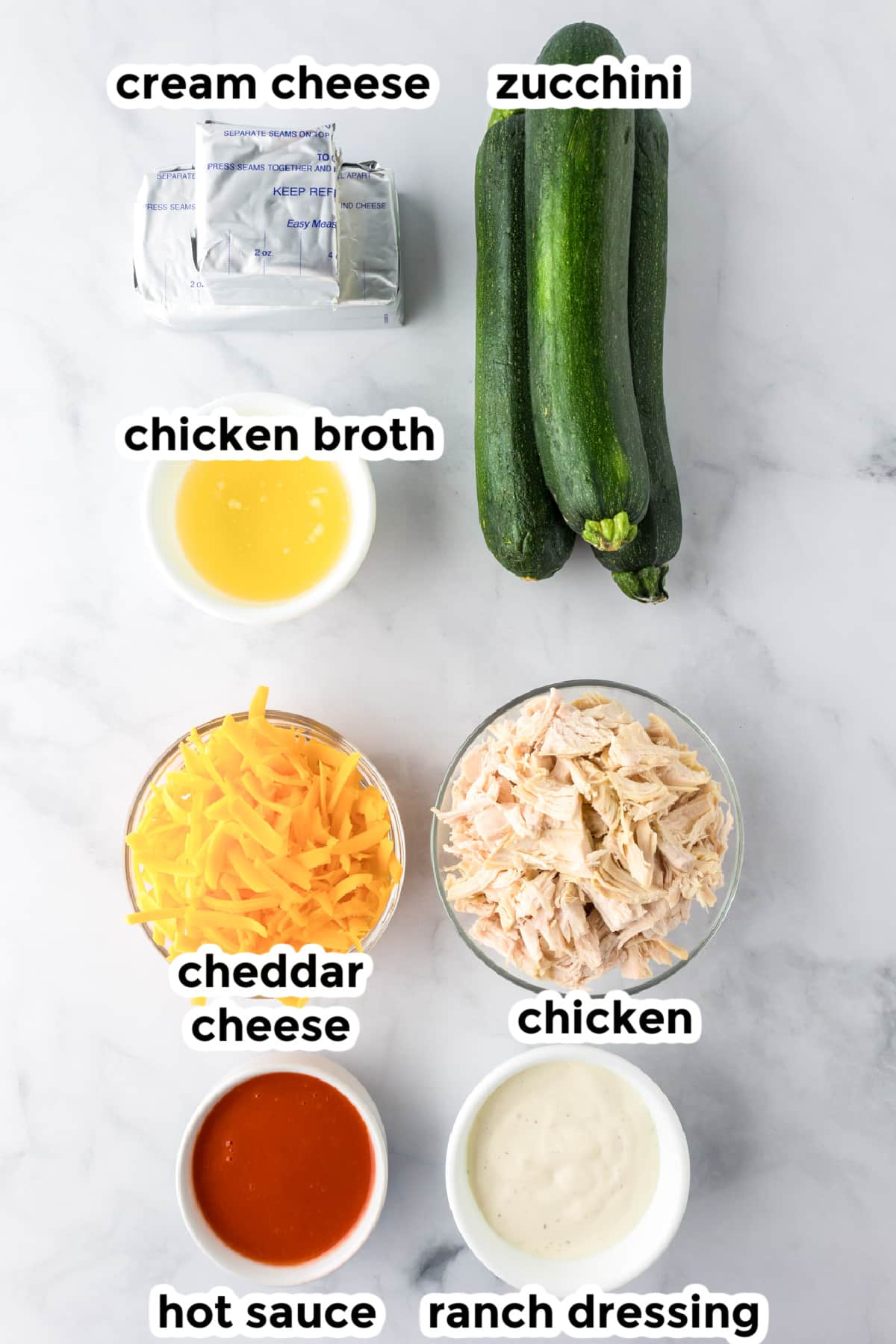 Ingredients for buffalo chicken stuffed zucchini boats in bowls with text labels.