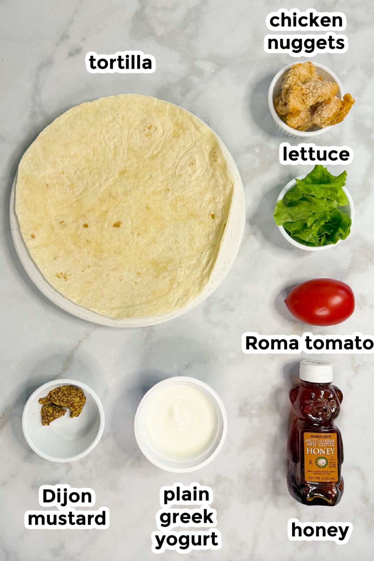 A flour tortilla, chicken nuggets, lettuce, Roma tomato, Dijon mustard, plain Greek yogurt, and honey are arranged on a white surface, each labeled with text.
