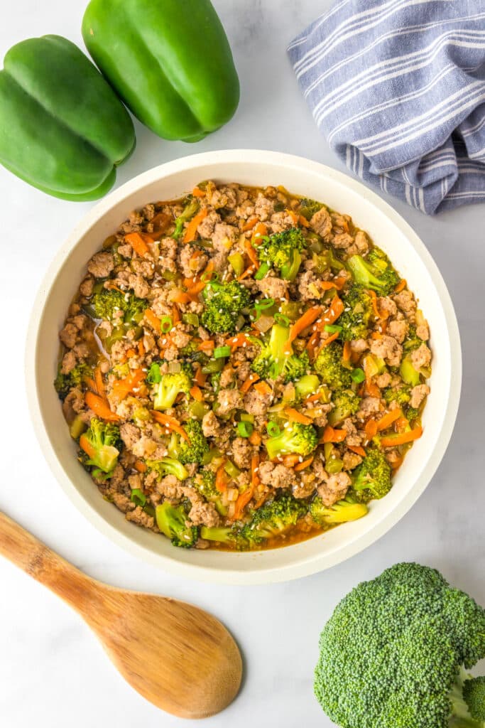 Finished stir fried ground turkey teriyaki mixed with vegetables in a bowl on a counter.