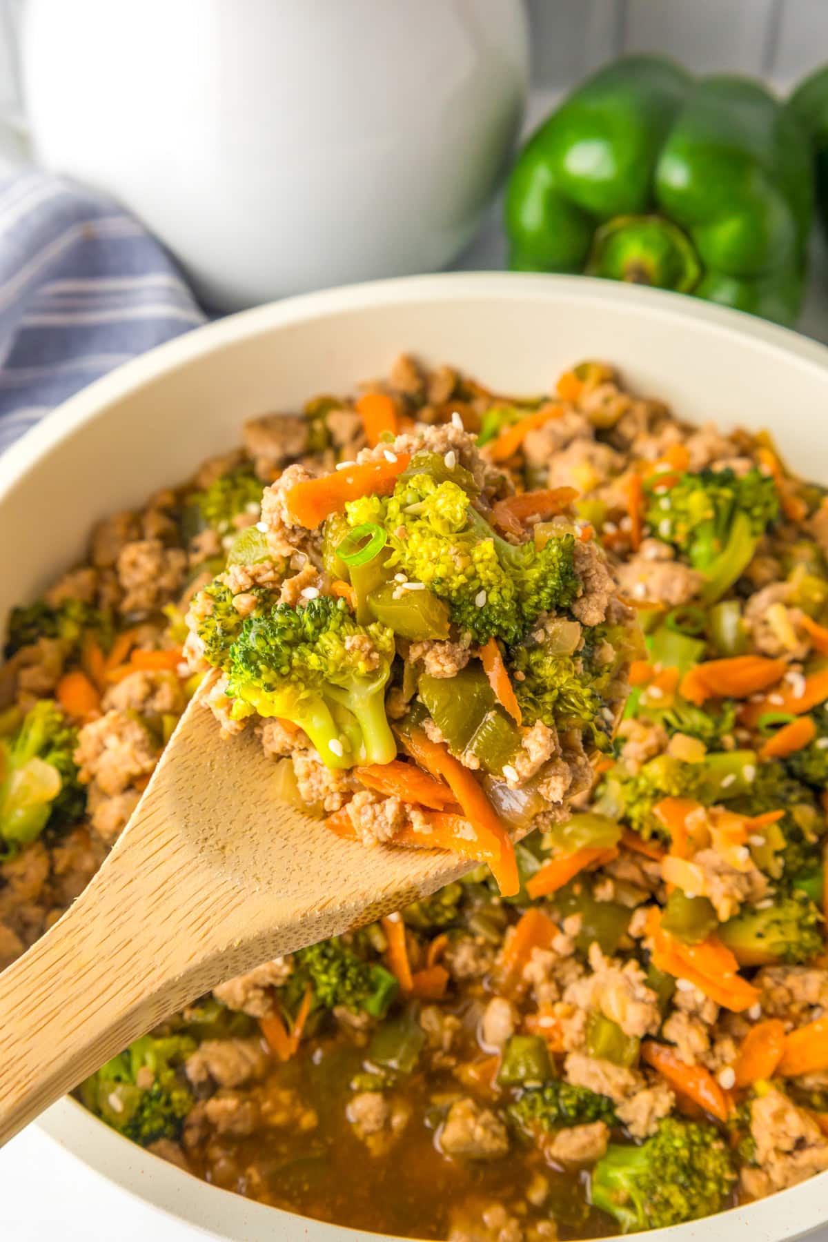 A wooden spoon holds a serving of ground turkey teriyaki over a pan.