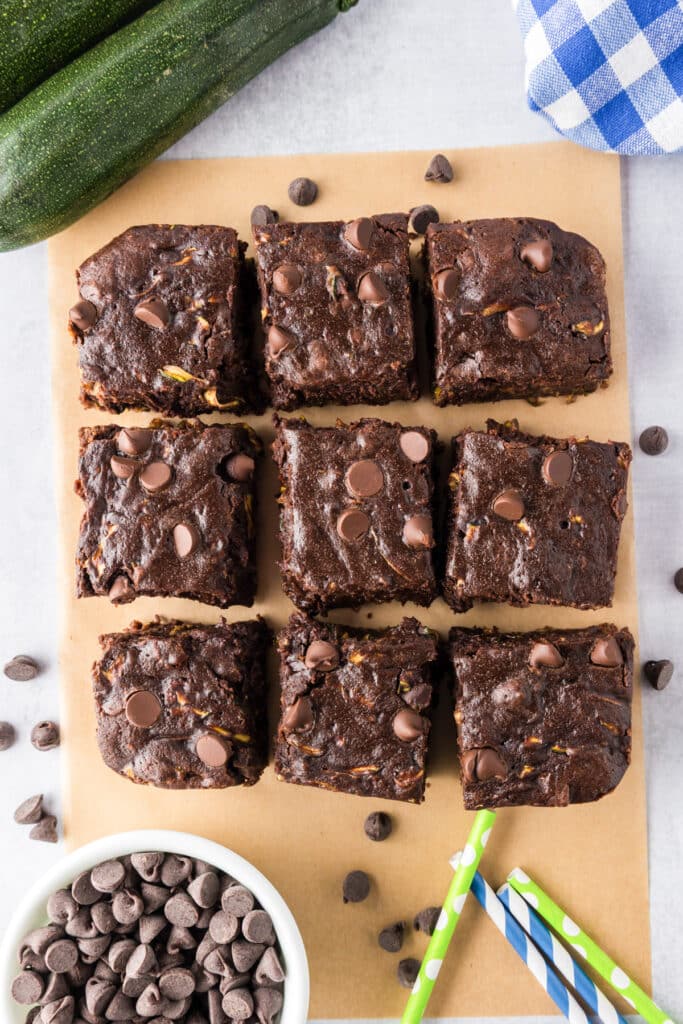 Nine chocolate chip zucchini brownies after being sliced on parchment paper.