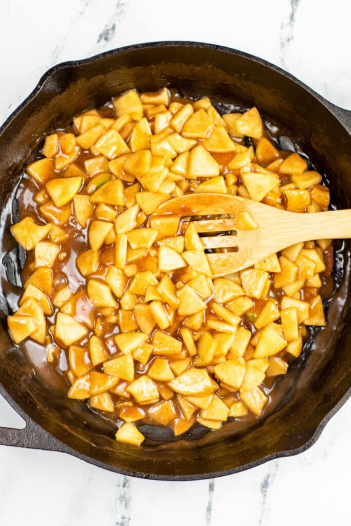 Diced cooked cinnamon apples being stirred for the filling of apple cookie cups.