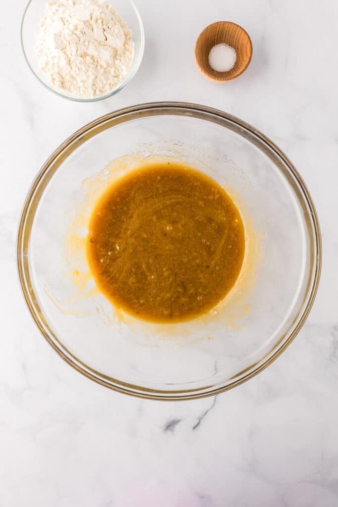 Wet ingredients mixed together for blondie batter with flour and salt nearby to finish the batter.