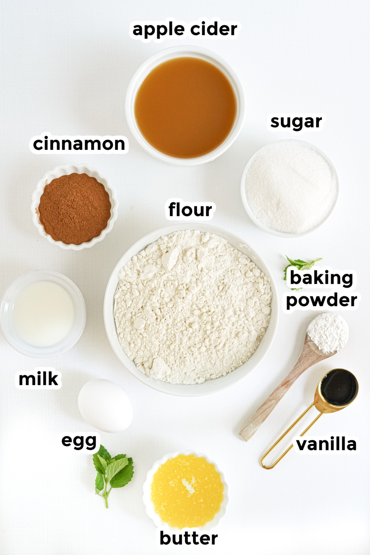 Top-down view of ingredients for baked apple cider donut holes with titles on a counter.