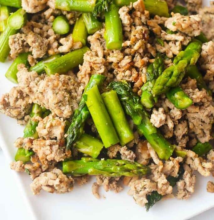 A plate of cooked ground turkey mixed with asparagus pieces.