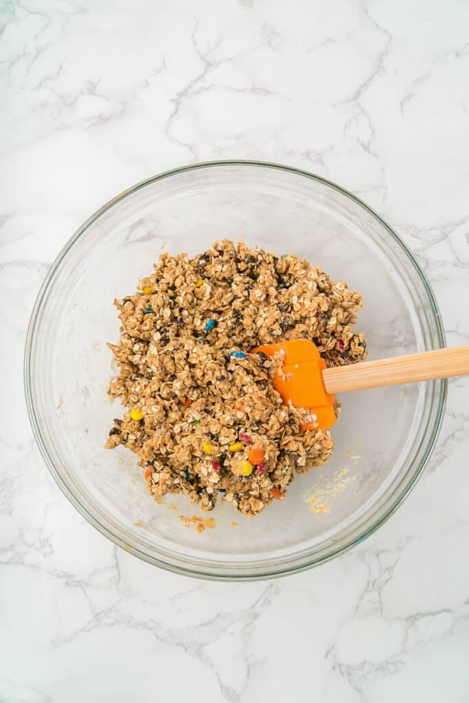 A glass bowl filled with mixed monster cookie energy ball dough.