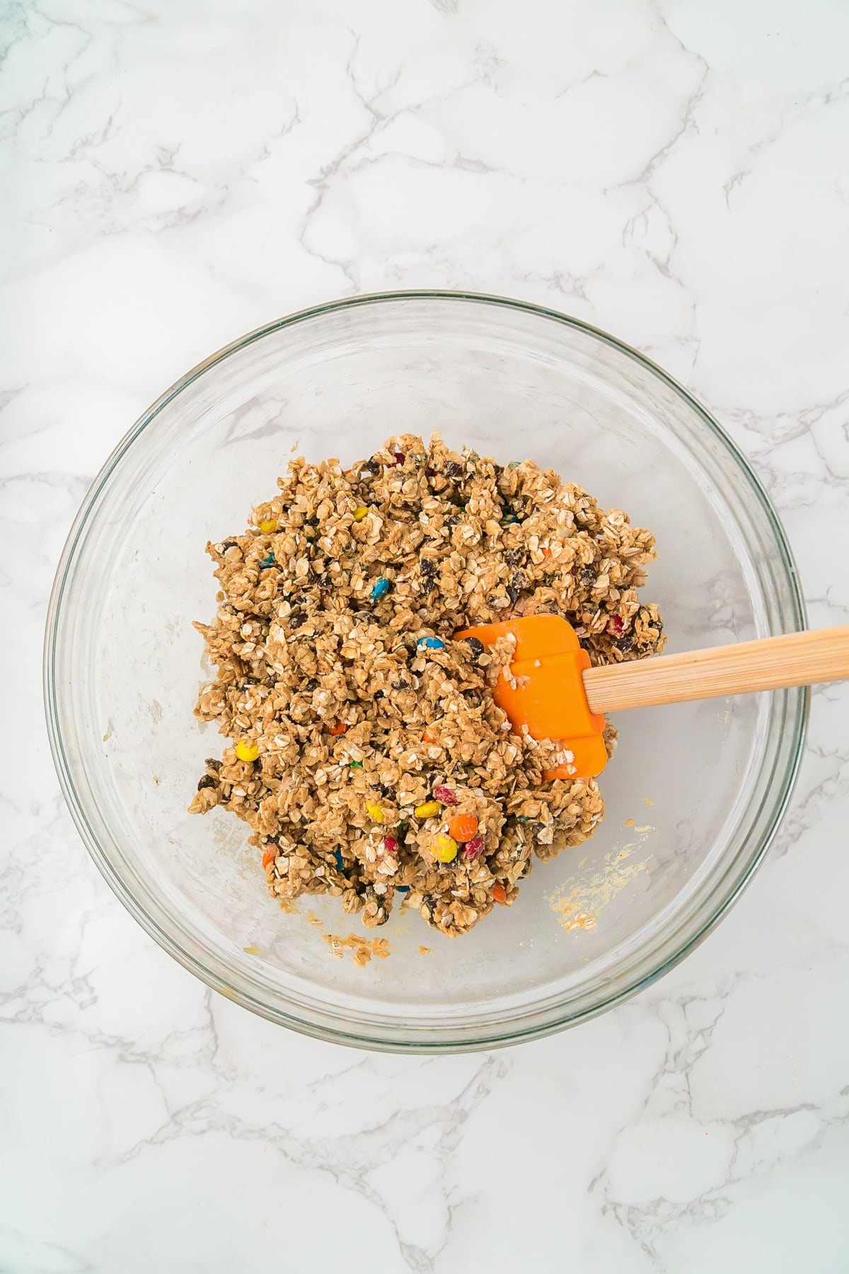 A glass bowl filled with mixed monster cookie energy ball dough.
