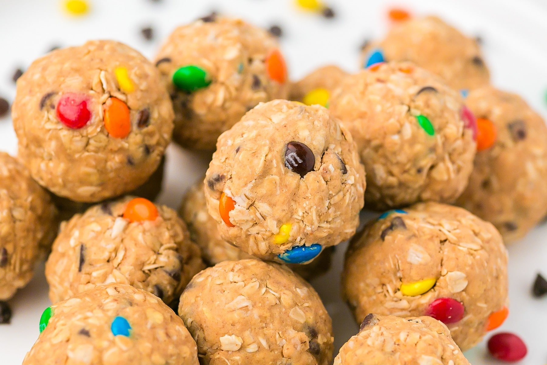 Close-up of monster cookie energy balls with colorful candy-coated chocolate pieces on a white surface.