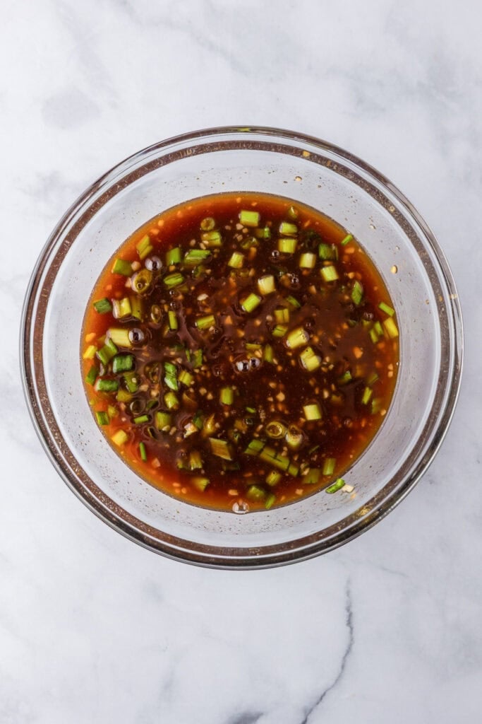 A glass bowl filled with the sauce for Slow Cooker BBQ Hawaiian Roll Chicken Sliders.