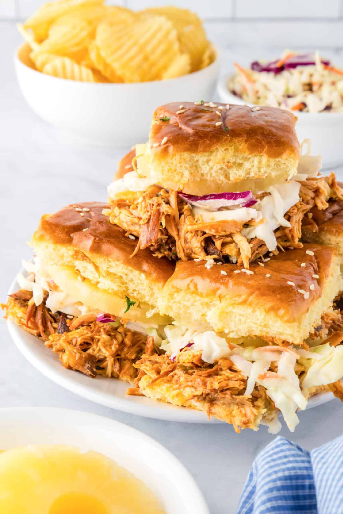 BBQ chicken sliders on Hawaiian rolls topped with coleslaw and pineapple.