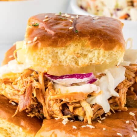 A Slow Cooker BBQ Hawaiian Roll Chicken Slider on a sesame bun topped with coleslaw.