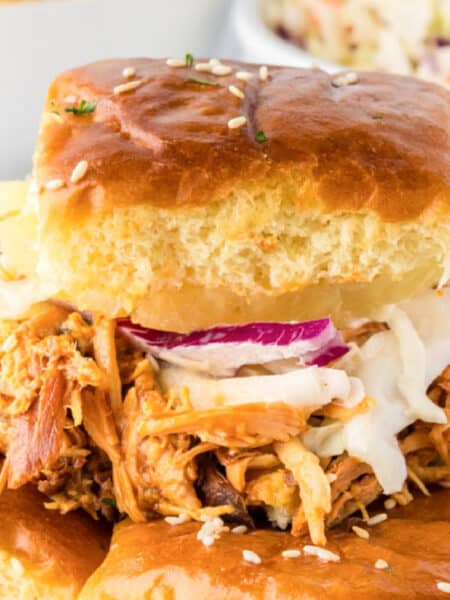 A Slow Cooker BBQ Hawaiian Roll Chicken Slider on a sesame bun topped with coleslaw.