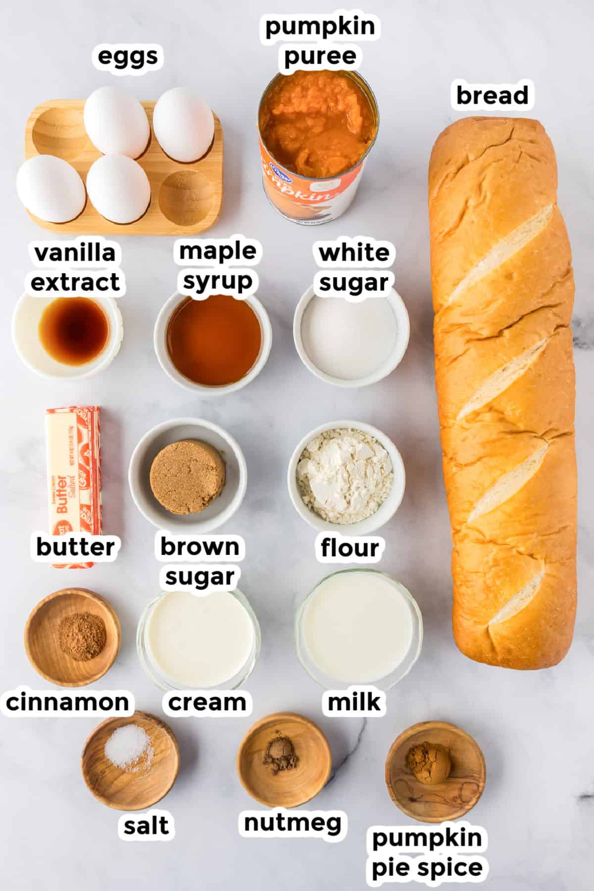 Top-down view of labeled ingredients in bowls for a pumpkin french toast casserole recipe.
