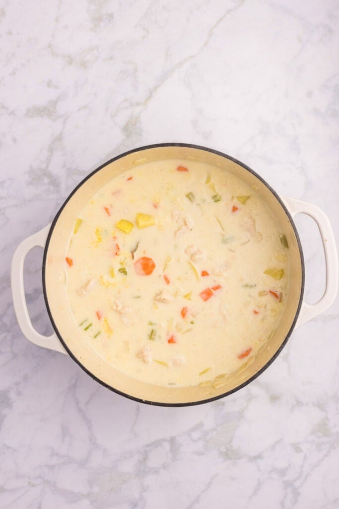 A white pot filled with creamy chicken stew after simmering.