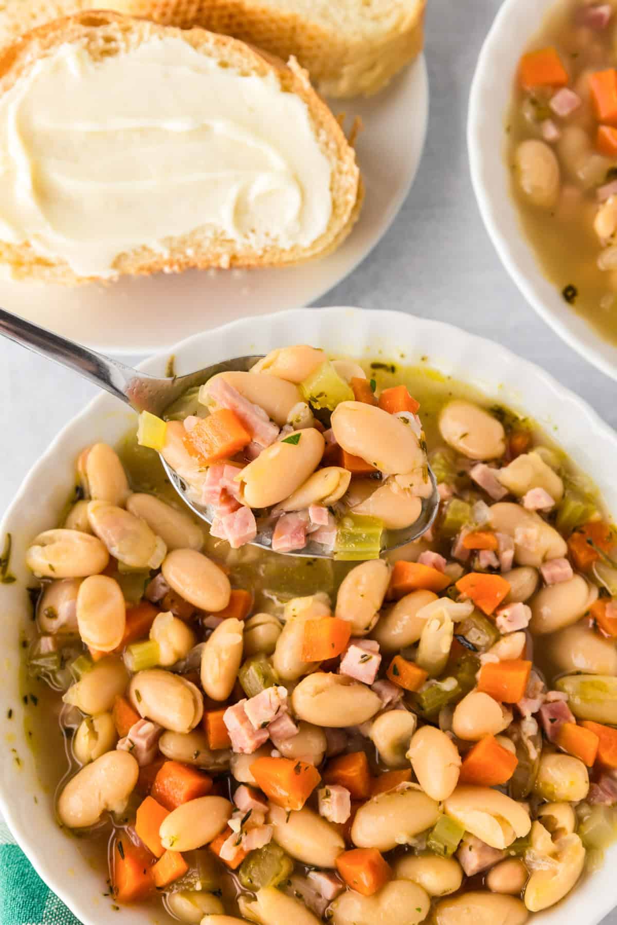 A bowl of white bean and ham soup with a spoon.