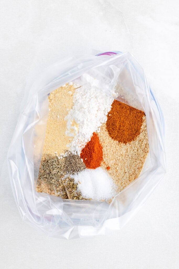 A plastic bag containing assorted dry spices and seasonings, perfect for making shake and bake air fryer chicken drumsticks.