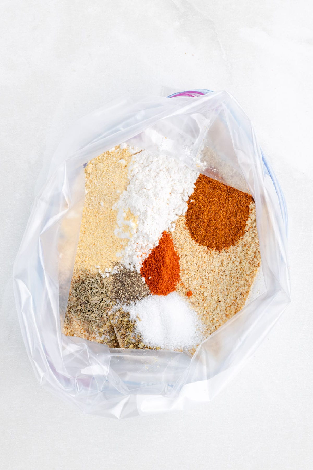 A plastic bag containing assorted dry spices and seasonings, perfect for making shake and bake air fryer chicken drumsticks.