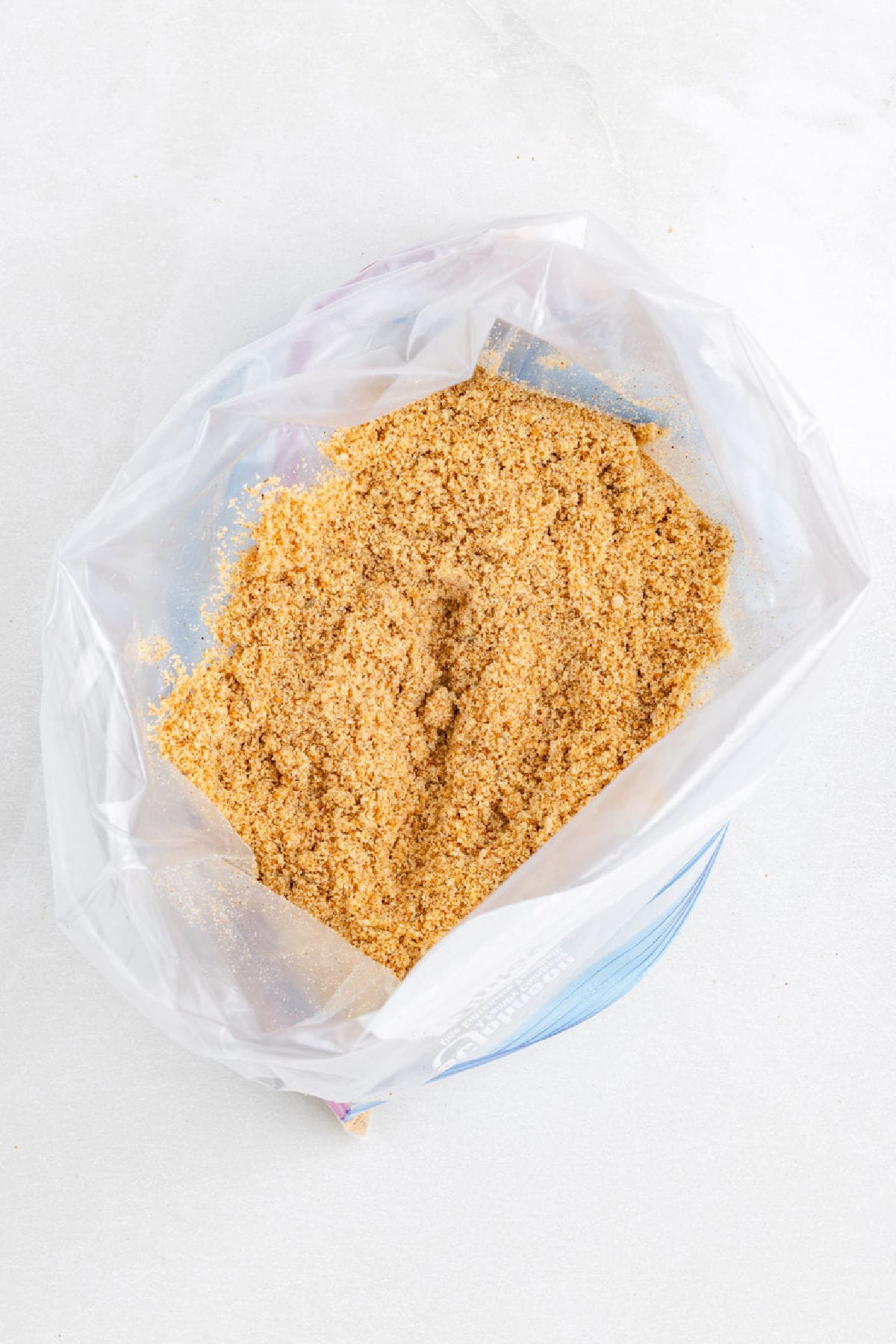 Open plastic bag filled with finely ground bread crumbs mixed with oil and seasoning for making shake and bake air fryer chicken drumsticks.
