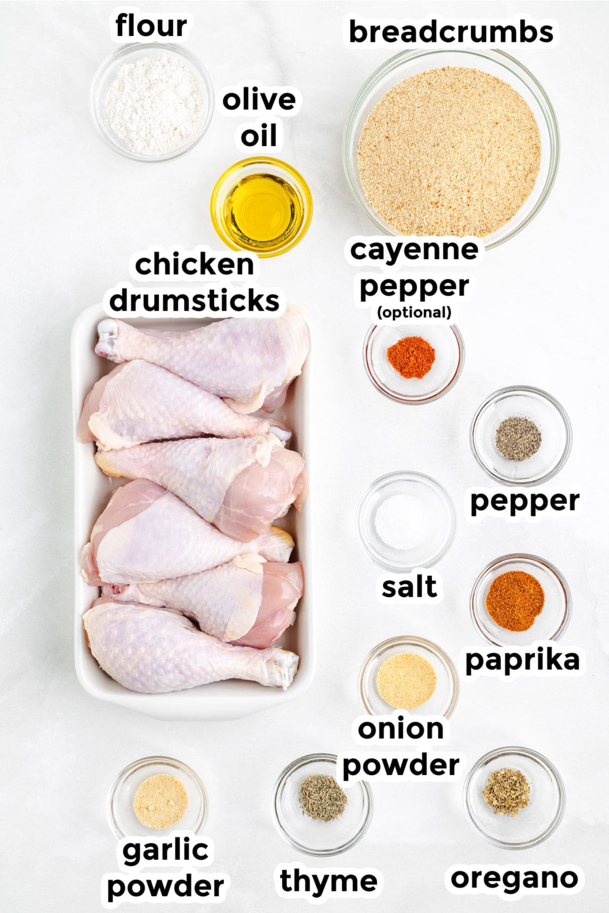Raw chicken drumsticks, flour, breadcrumbs and spices labeled on a counter for air fryer chicken drumsticks.