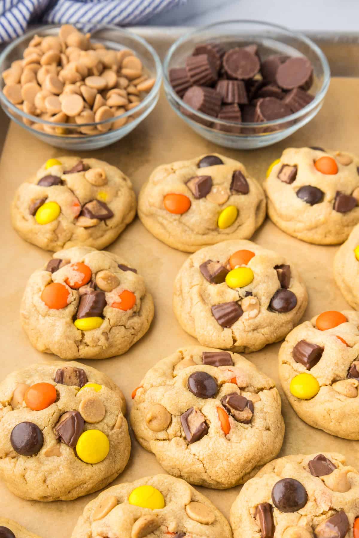 A tray of Reese's Pieces peanut butter cookies topped with colorful candies and pieces of peanut butter cups.