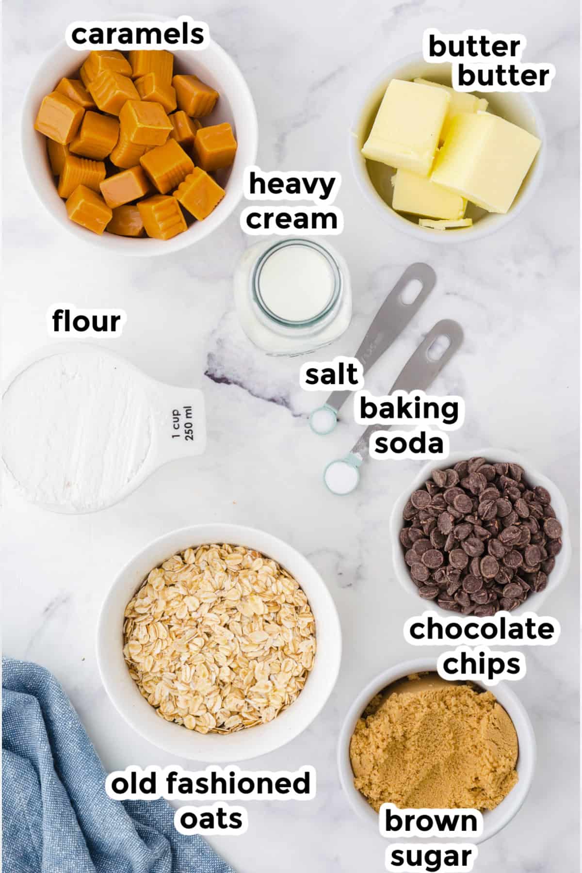 Bowls of caramels, butter, flour, heavy cream, salt, baking soda, chocolate chips, old fashioned oats, and brown sugar to make homemade carmelitas.