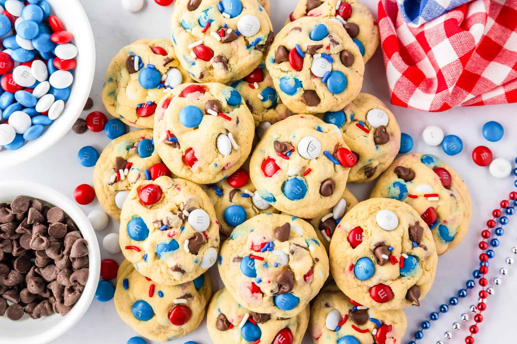 A pile of cookies with red, white, and blue M&M candies and chocolate chips.