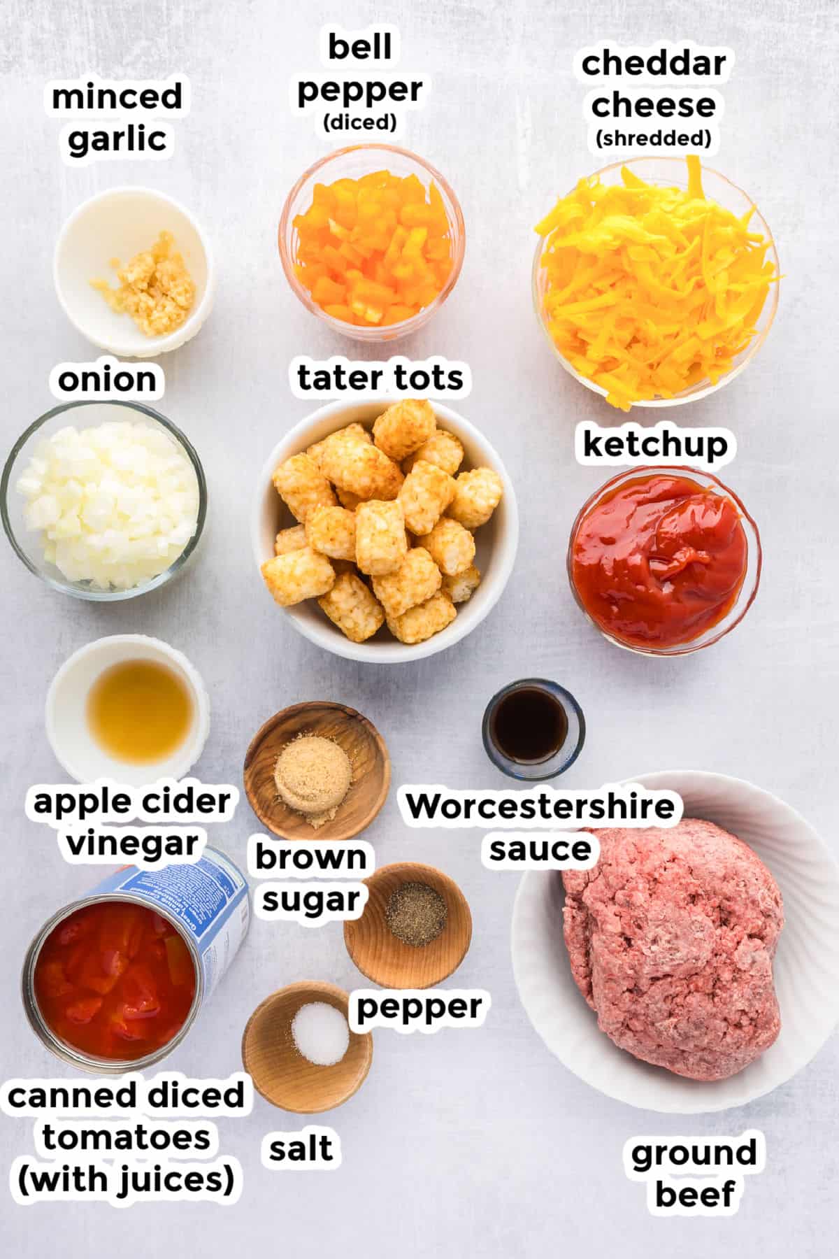 Ingredients for a tater tot casserole in bowls are arranged on a counter with labels.