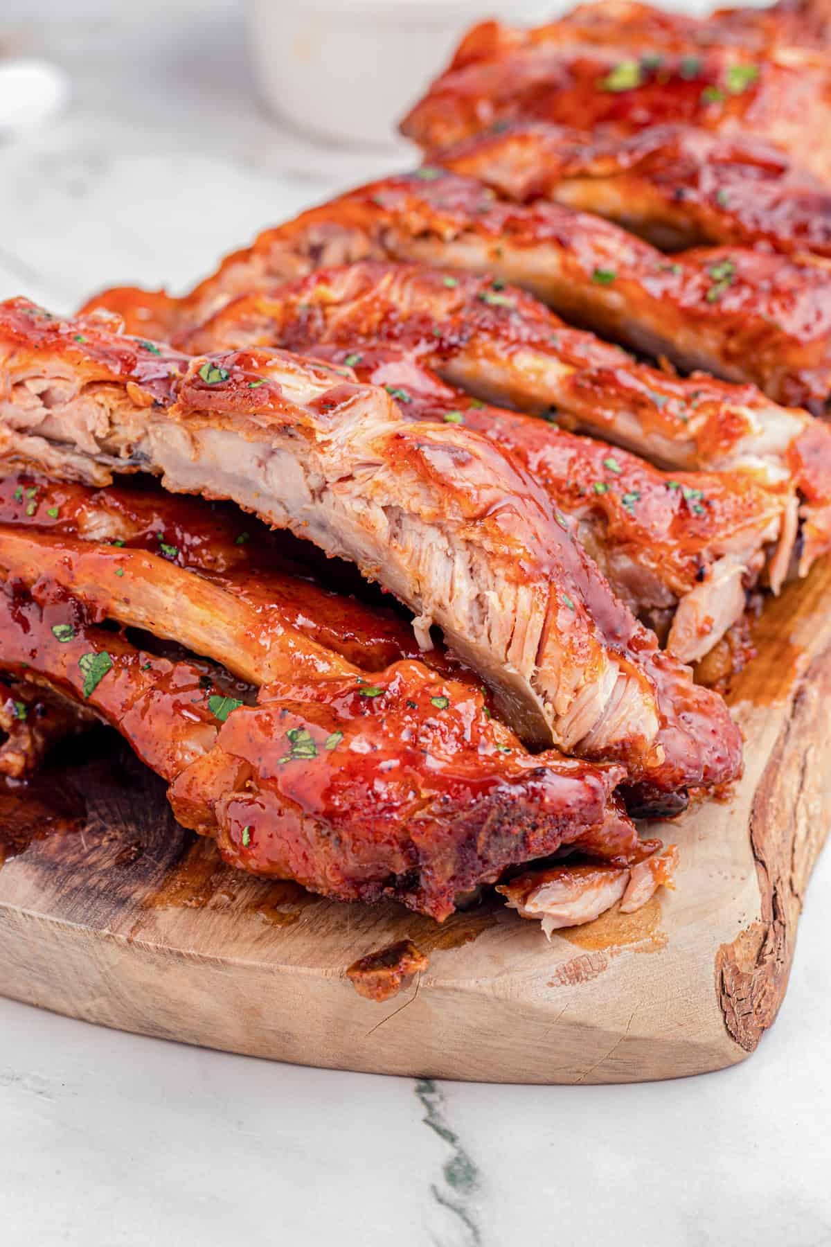 Sliced slow cooker garlic honey ribs on a wooden cutting board.