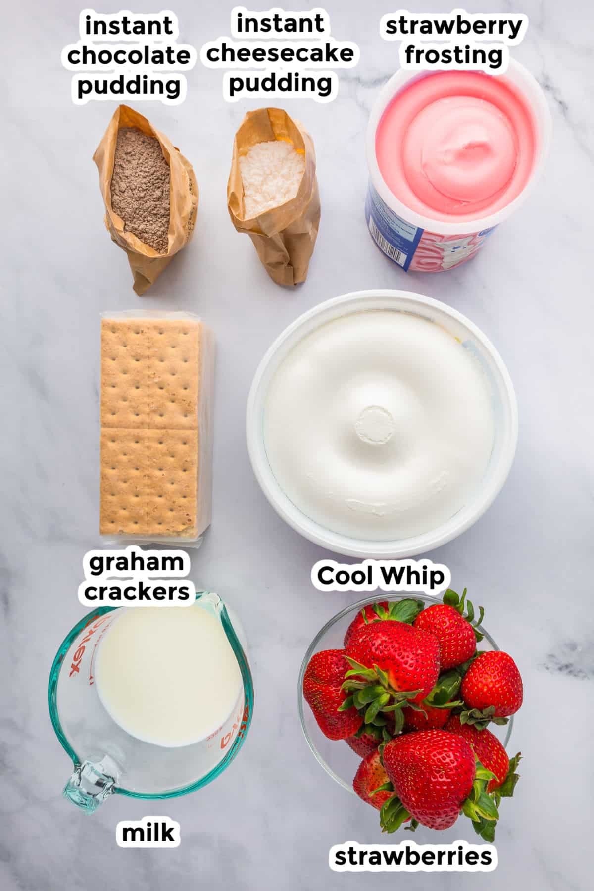 Ingredients for strawberry chocolate eclair cake arranged on a marble surface with labels.