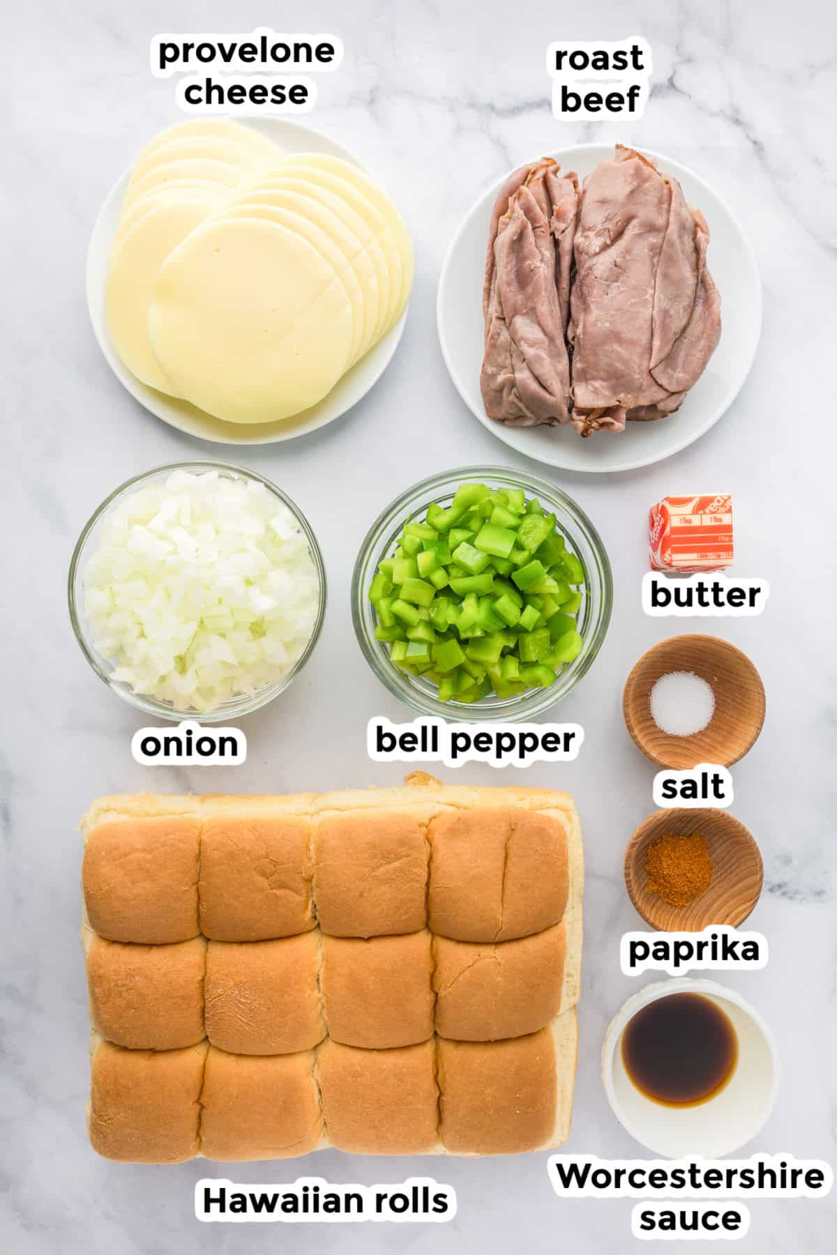 Ingredients for philly cheesesteak sliders on a counter with text labels.