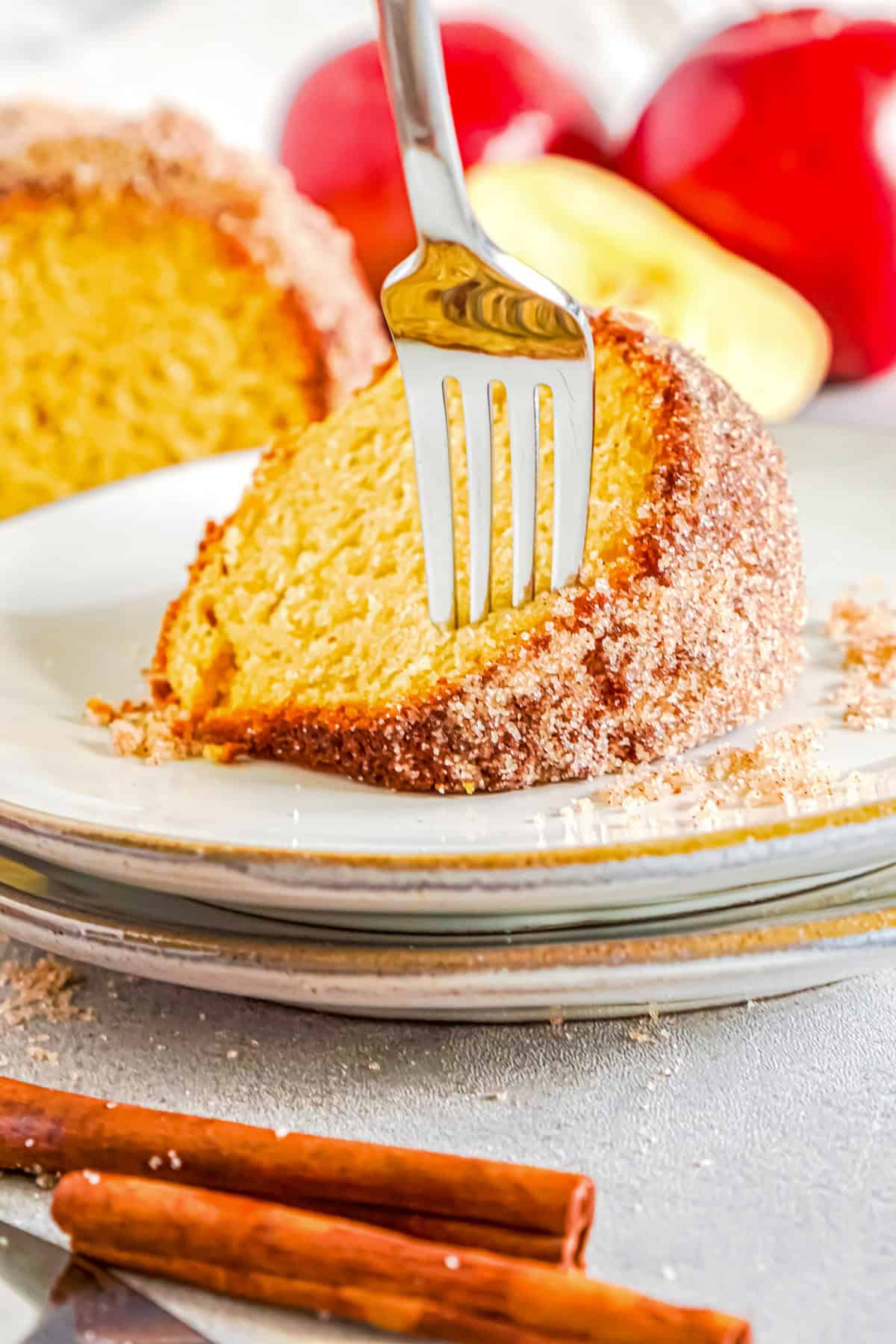 A fork taking a bite from a slice of apple cider donut cake on a plate.