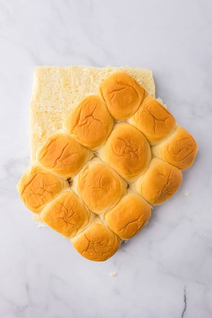Hawaiian rolls after being sliced horizontally for chicken parmesan sliders on a counter.