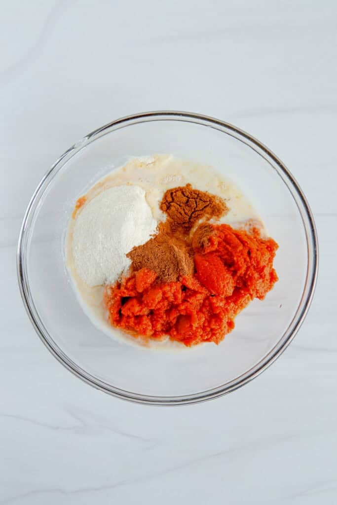 A glass bowl with pumpkin, instant vanilla pudding, milk and pumpkin pie spice for pumpkin pie dip.