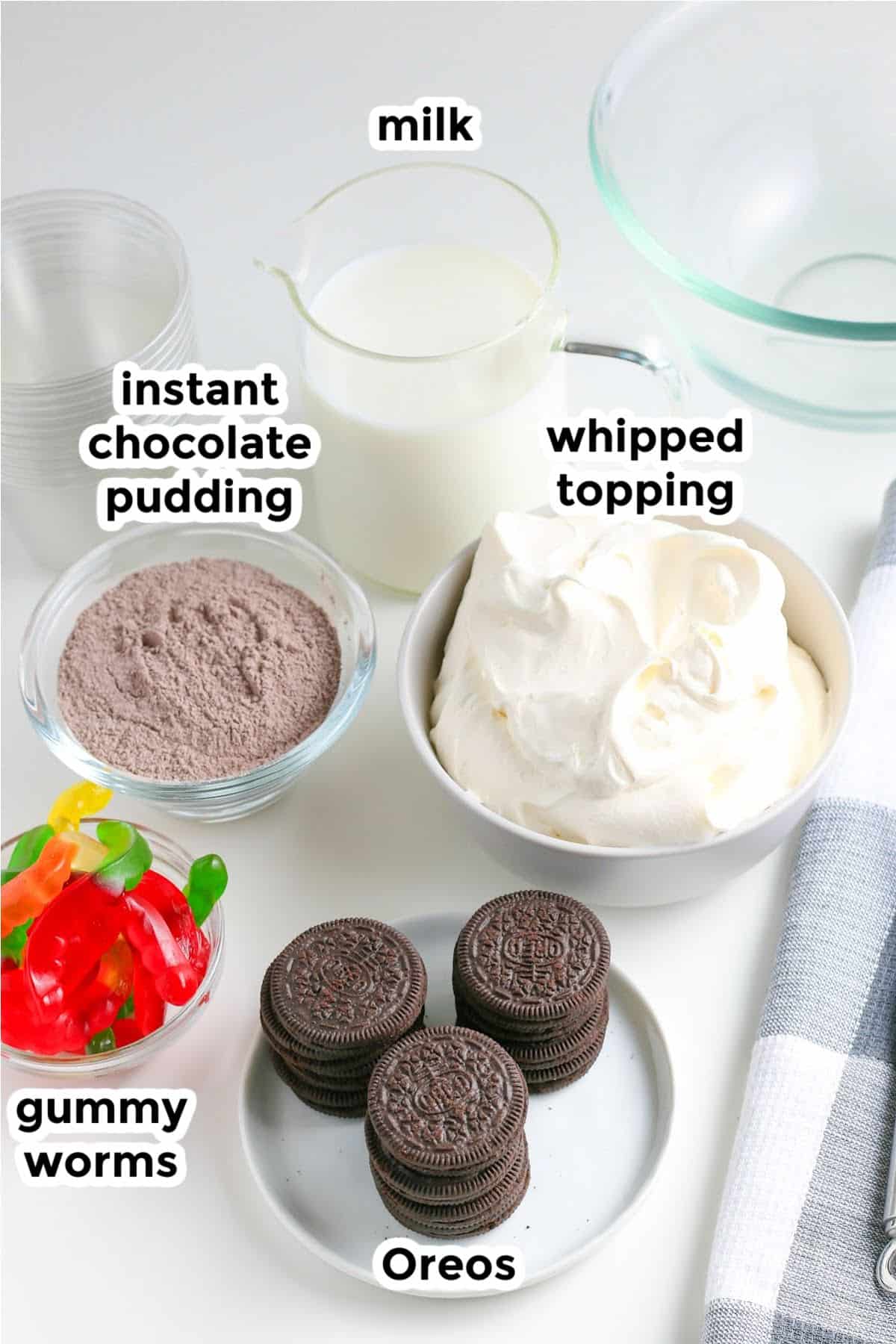 Ingredients for chocolate dirt cups inclusing instant chocolate pudding mix, milk, whipped topping, Oreos, and gummy worms.
